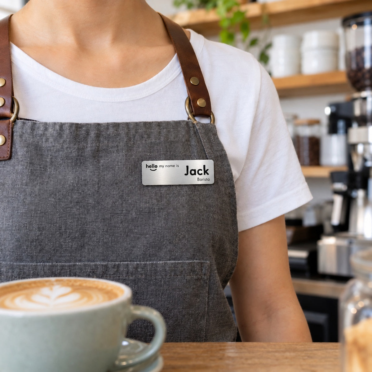 Silver Hello My Name Is name badge, Option 3, worn on a barista's apron