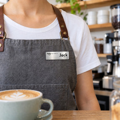 Silver Hello My Name Is name badge, Option 3, worn on a barista's apron