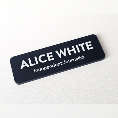 Acrylic name badge – black matte badge with white name ALICE WHITE and Independent Journalist line, on a white surface