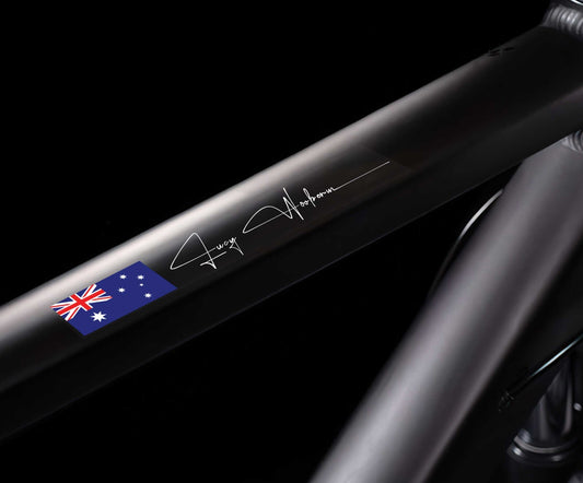 Custom flag and name sticker in signature script applied to a black bicycle top tube, with Australian flag